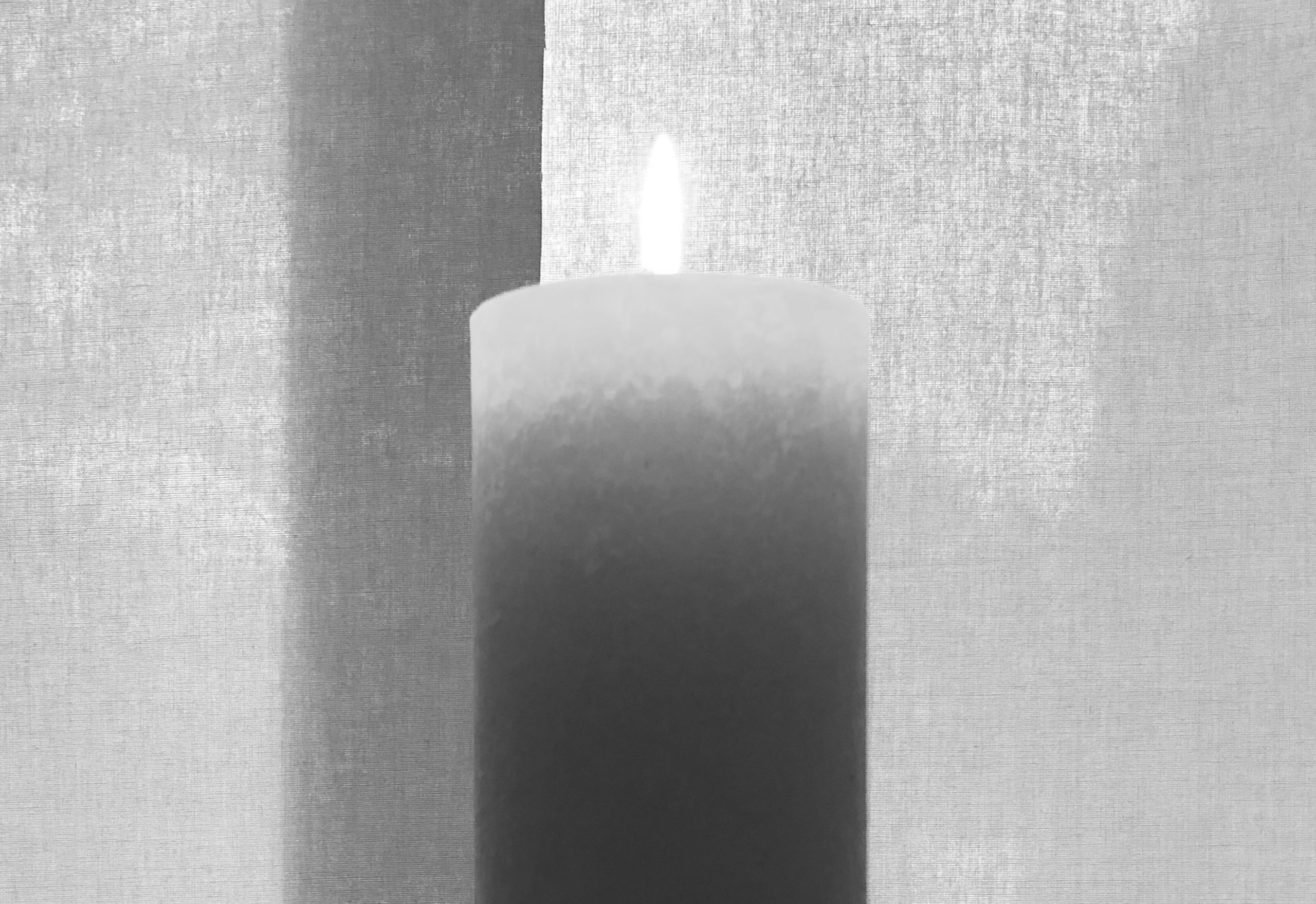 Brennende Kerze in schwarz-weiß, im Hintergrund Leinenstruktur
